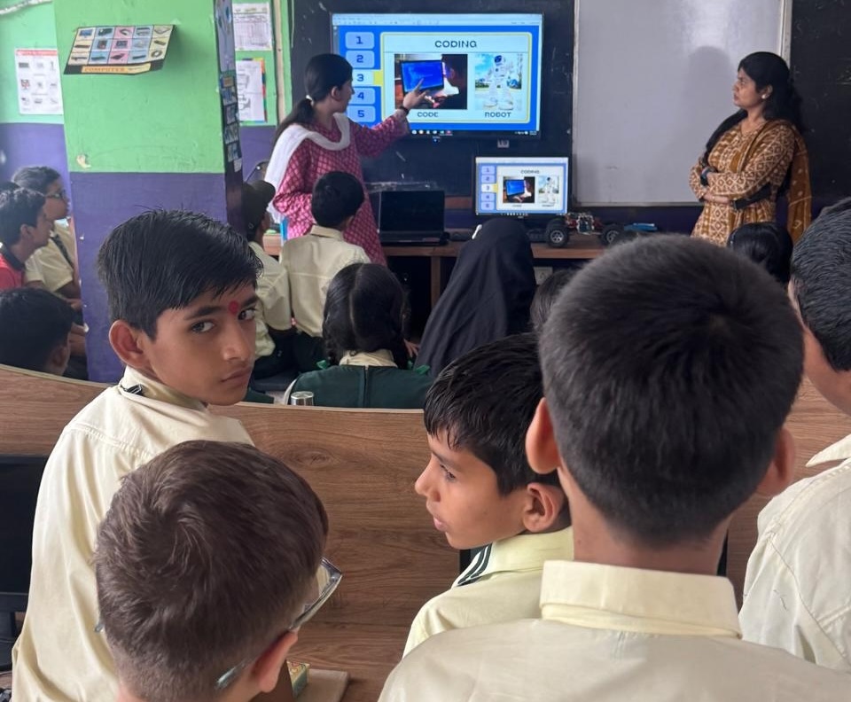 DreamBig volunteer teaching a coding lesson to students on a projector screen